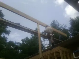 Carpenter setting a ridge beam over a new addition frame — Ice Dam Removal by Roofing Brothers in Parker