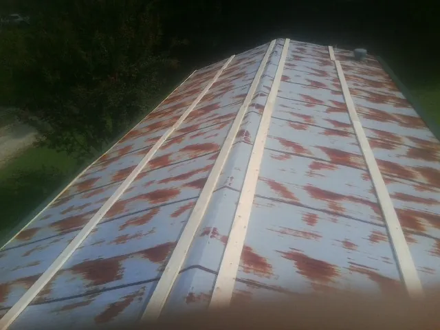 Rusted metal roof panels with new wood purlins before replacement in Parker