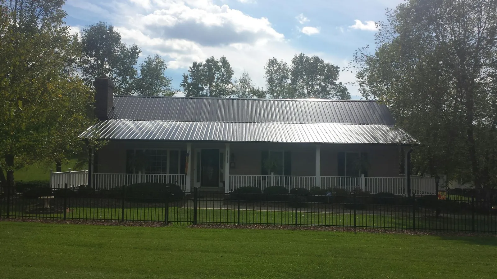 Gray metal roof on a brick ranch with a full width front porch — Gutter Guard Installation work by our crew in Parker