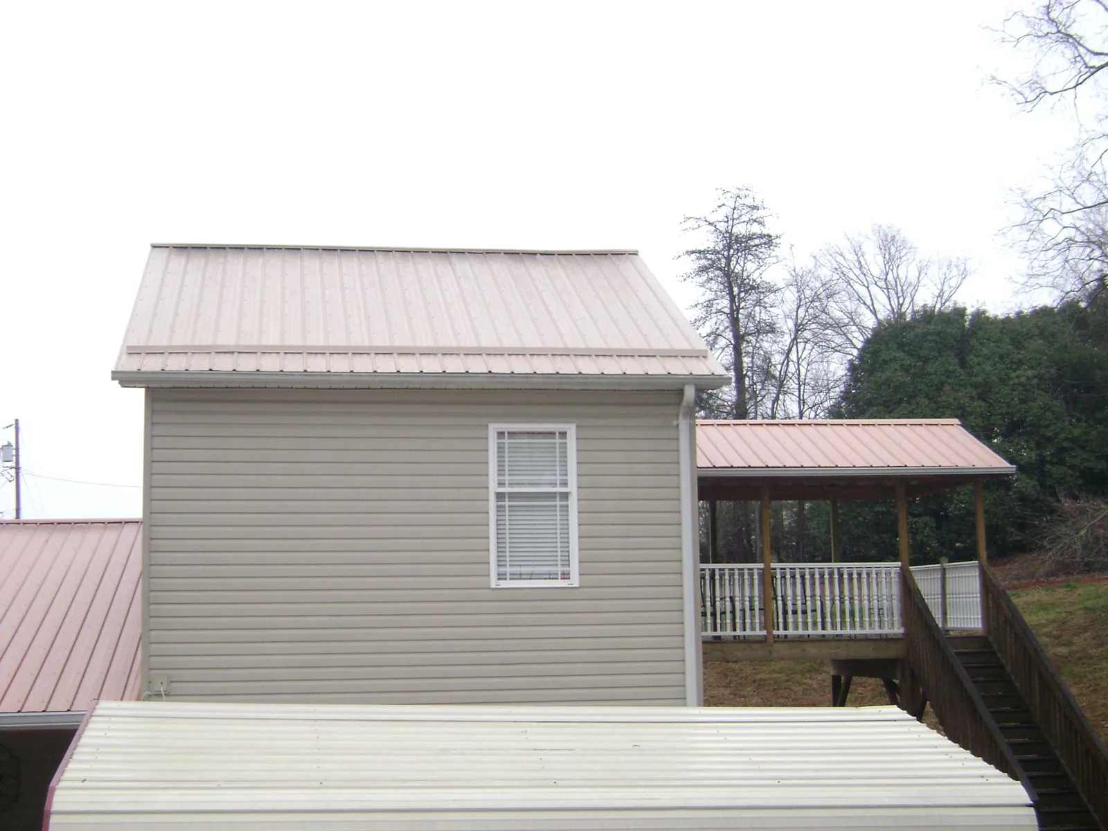 Tan metal roofs on a two story addition and attached porch, from a Roof Replacement job in Parker